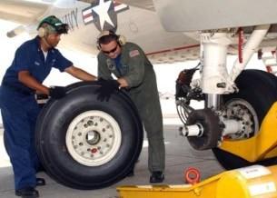 New high-performance aircraft tire being inspected by engineers on a jet aircraft.