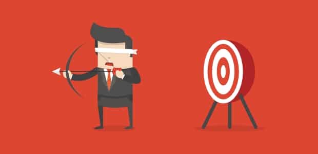 Blindfolded businessman aiming with a bow at a target, symbolizing focus and goal achievement.